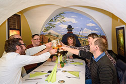 Prost! Auf einen gemütlichen Abend in der Alten Post. Freunde stoßen mit einem Glas Bier in einer Nische des Gasthauses an